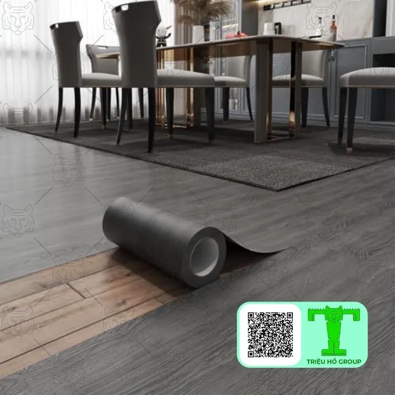 Cuộn sàn nhựa vinyl màu xám đang được trải ra trên nền nhà vân gỗ trong không gian phòng ăn hiện đại