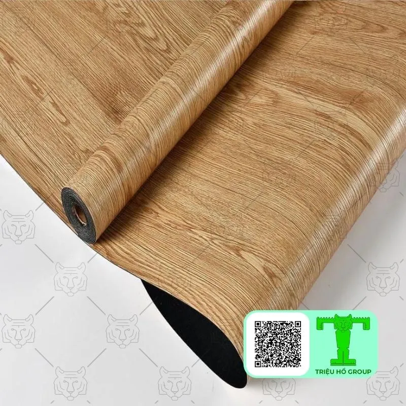 Cuộn sàn nhựa vinyl vân gỗ màu nâu nhạt đang được trải ra, lộ mặt dưới màu đen trên nền trắng