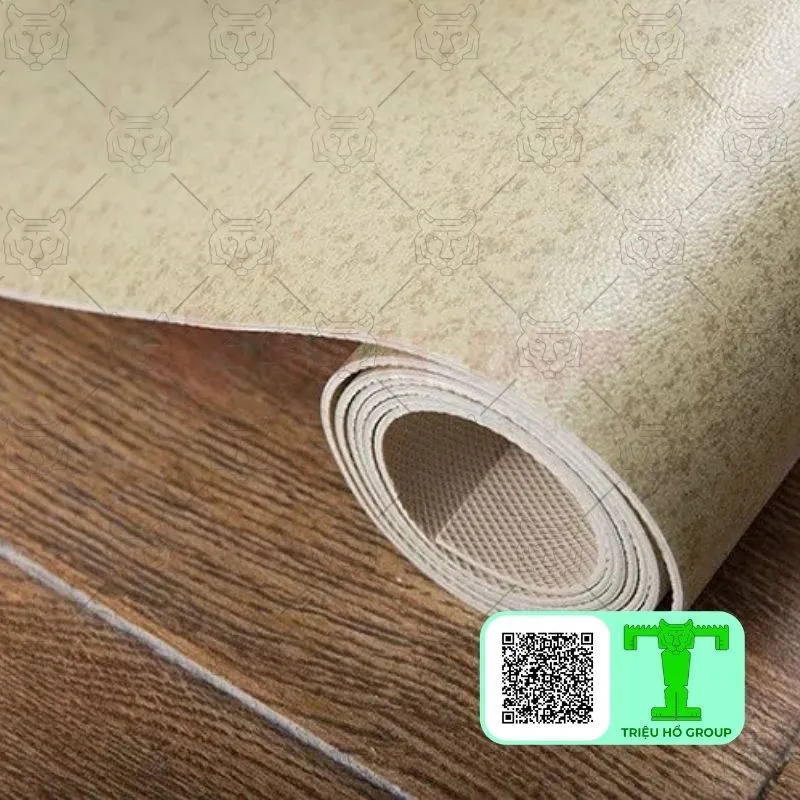 Cuộn sàn nhựa vinyl màu be nhạt đang trải ra trên nền gỗ, với mã QR và logo ở góc dưới bên phải