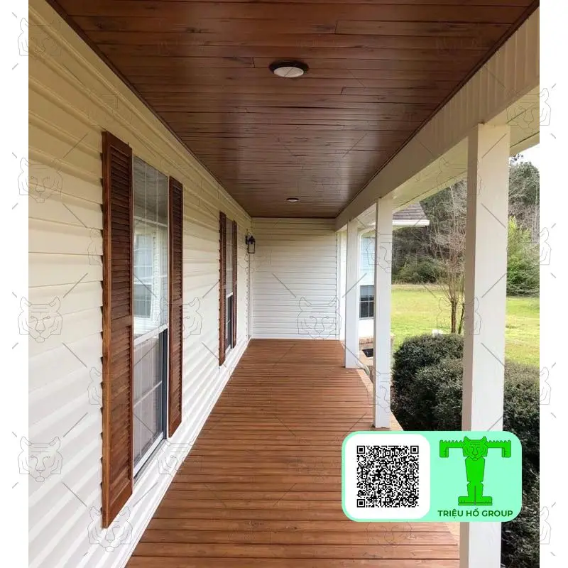 Sàn gỗ Conwood màu nâu và trần ốp gỗ trên hiên nhà, với tường ốp ván màu kem và cửa sổ có chớp gỗ