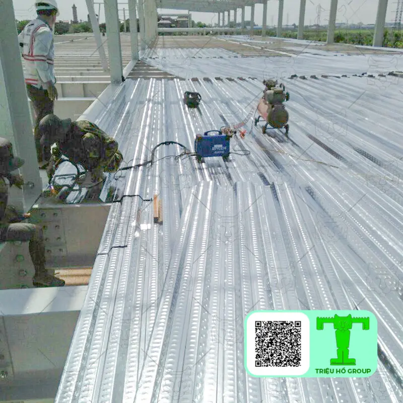 Công nhân đang lắp đặt sàn deck trên kết cấu khung thép tại công trường xây dựng