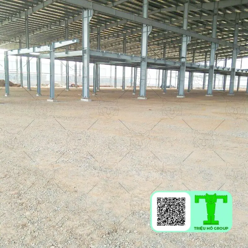 Khung thép nhà xưởng đang xây dựng với nhiều tầng dầm và sàn deck kim loại trên nền đất