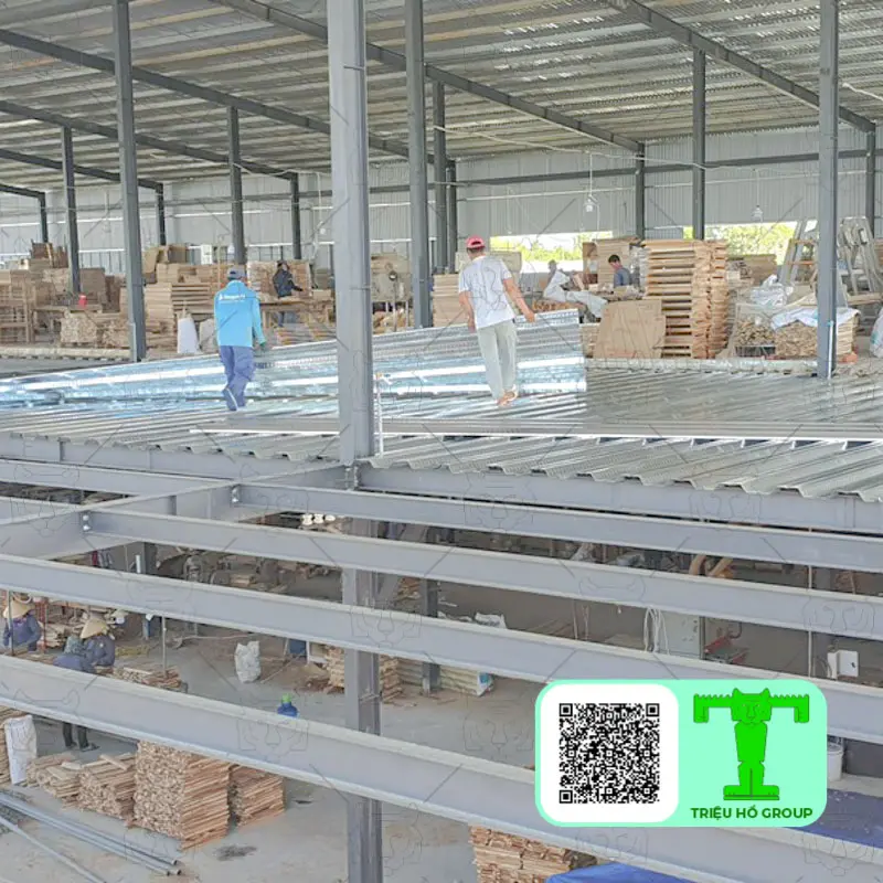 Công trình nhà xưởng với kết cấu thép và sàn deck đang được lắp đặt, có công nhân làm việc