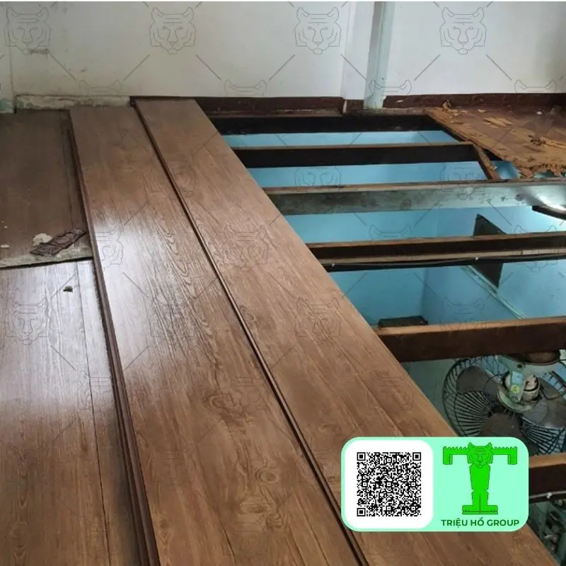 Các tấm ván sàn nhựa PVC màu nâu vân gỗ đang được lắp đặt trên hệ khung của một gác lửng